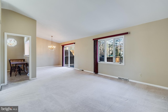 carpeted spare room featuring a notable chandelier, a healthy amount of sunlight, and vaulted ceiling