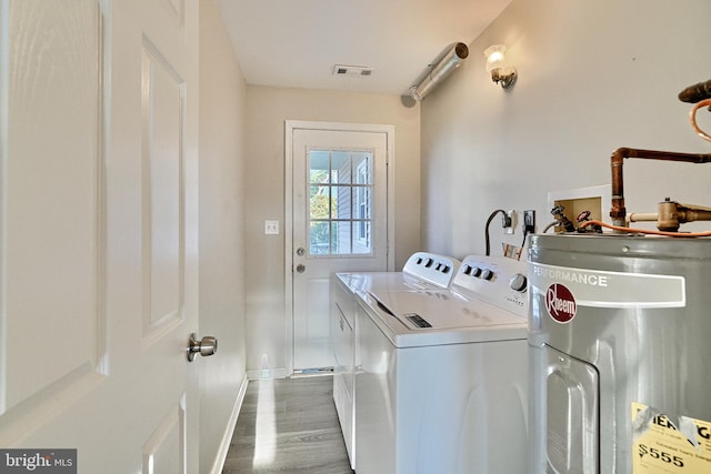 laundry area featuring washing machine and clothes dryer, dark hardwood / wood-style flooring, and water heater