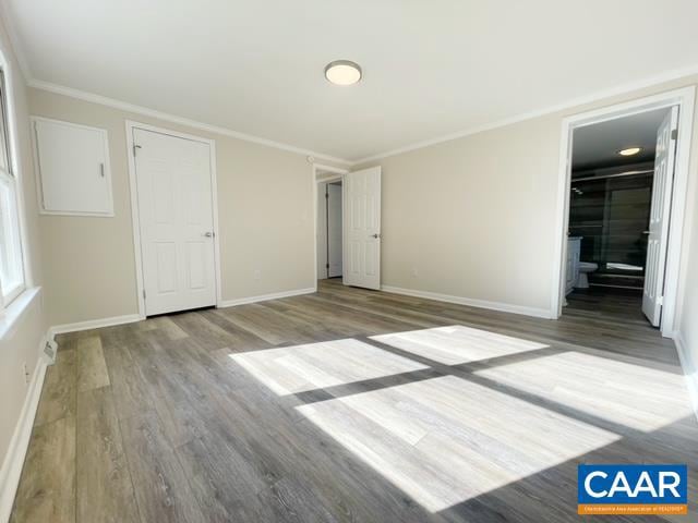 unfurnished bedroom featuring crown molding, hardwood / wood-style floors, and ensuite bathroom