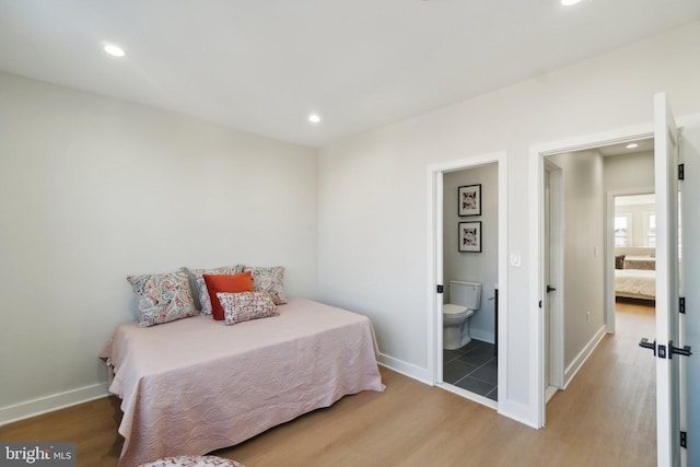 bedroom with connected bathroom and light hardwood / wood-style flooring