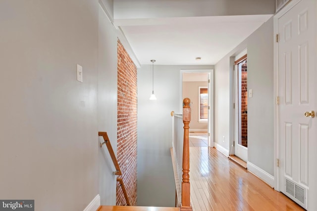 hall featuring brick wall and light hardwood / wood-style flooring