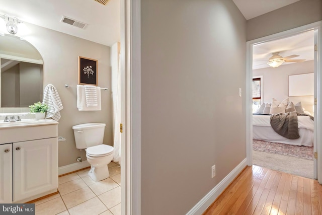 bathroom with ceiling fan, vanity, wood-type flooring, and toilet