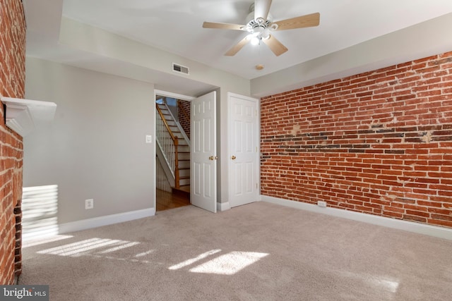 unfurnished bedroom with light carpet, ceiling fan, and brick wall