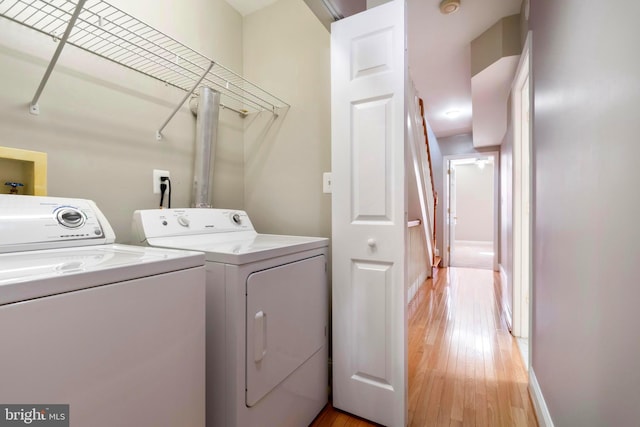 clothes washing area with hardwood / wood-style floors and washer and dryer