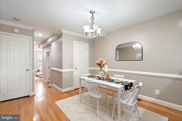 dining room with light hardwood / wood-style flooring, ornamental molding, and a notable chandelier