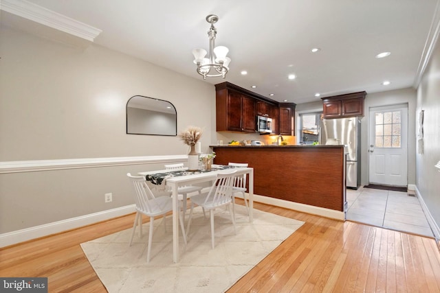 dining room with crown molding, light hardwood / wood-style floors, and a notable chandelier