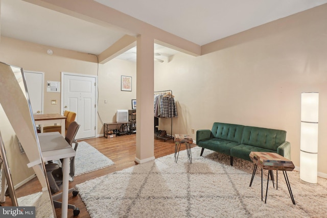 living room featuring baseboards, wood finished floors, and beamed ceiling