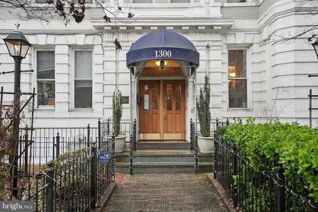 property entrance featuring stone siding and fence