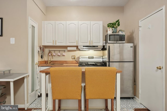 kitchen featuring stainless steel appliances, white cabinetry, a sink, and under cabinet range hood