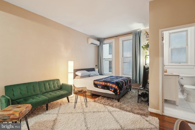 bedroom featuring an AC wall unit, baseboards, and wood finished floors