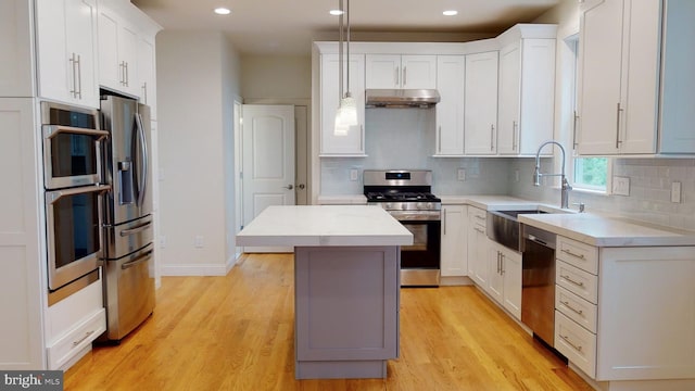 kitchen featuring appliances with stainless steel finishes, light wood-type flooring, sink, white cabinets, and a kitchen island