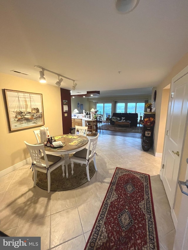 dining area with tile patterned floors and track lighting