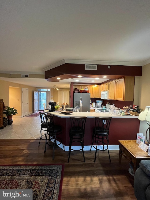 kitchen with a kitchen breakfast bar, kitchen peninsula, light hardwood / wood-style flooring, and stainless steel appliances