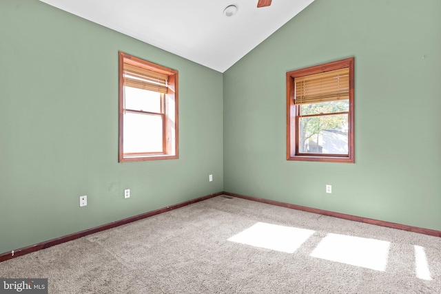 spare room featuring carpet flooring, plenty of natural light, and vaulted ceiling