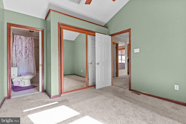 unfurnished bedroom featuring ensuite bath, ceiling fan, light colored carpet, lofted ceiling, and a closet