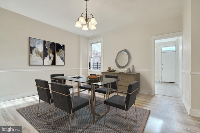 dining space with an inviting chandelier and light hardwood / wood-style flooring