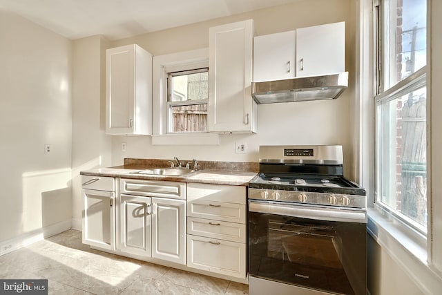 kitchen featuring plenty of natural light, stainless steel gas range oven, white cabinetry, and sink