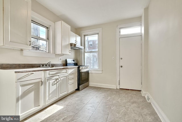 kitchen with gas range, white cabinetry, and sink