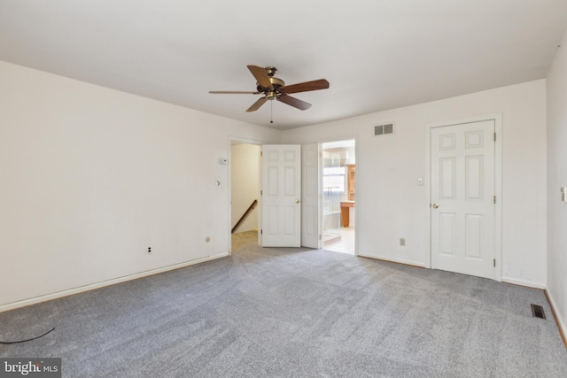 unfurnished bedroom featuring ceiling fan, light colored carpet, and ensuite bath