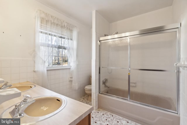 full bathroom with tile patterned floors, vanity, tile walls, enclosed tub / shower combo, and toilet