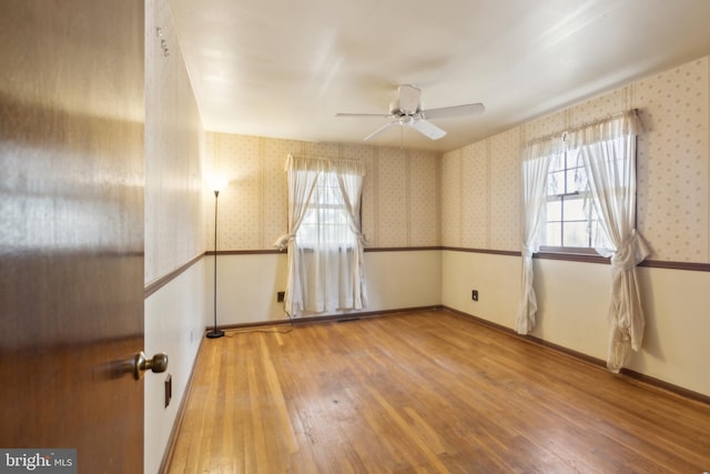 spare room featuring ceiling fan, a healthy amount of sunlight, and light hardwood / wood-style flooring