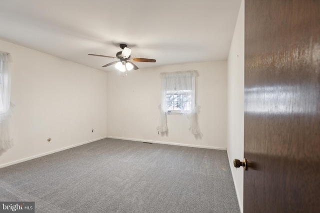 spare room featuring dark colored carpet and ceiling fan