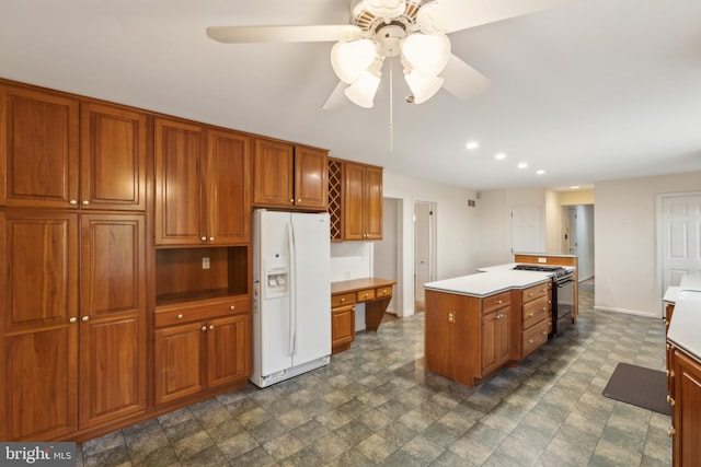 kitchen with gas range, ceiling fan, white fridge with ice dispenser, a center island, and built in desk