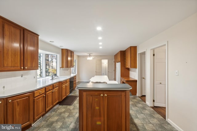 kitchen featuring a center island, backsplash, ceiling fan, and sink