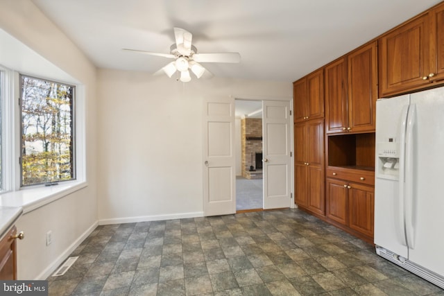 kitchen with ceiling fan, white refrigerator with ice dispenser, and a fireplace