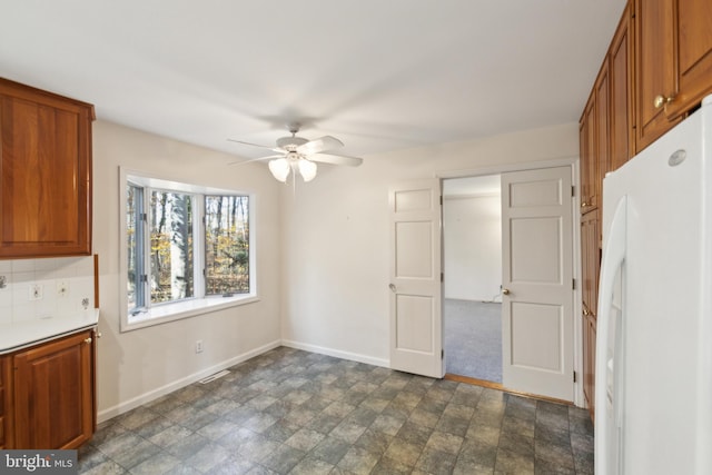 kitchen with tasteful backsplash, white fridge, and ceiling fan