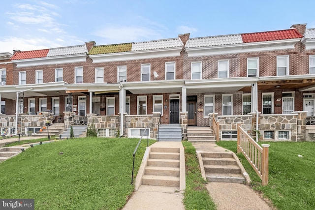 townhome / multi-family property featuring a front lawn and covered porch