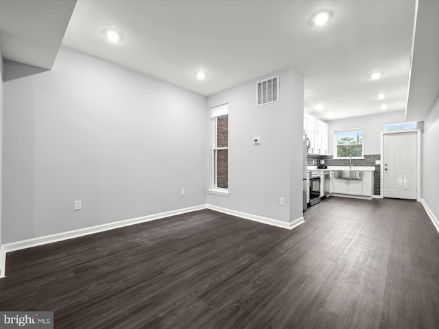 unfurnished living room featuring sink and dark wood-type flooring