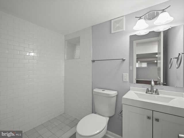 bathroom featuring a tile shower, vanity, and toilet