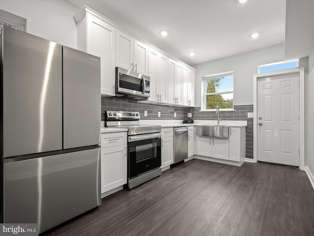 kitchen featuring sink, dark wood-type flooring, stainless steel appliances, backsplash, and white cabinets