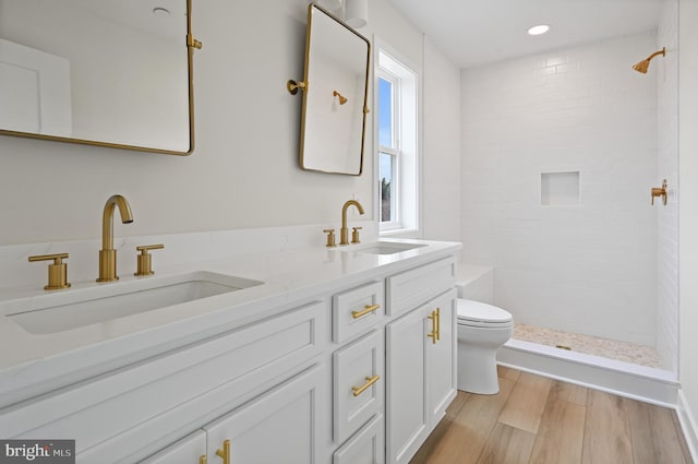 bathroom featuring vanity, toilet, wood-type flooring, and a tile shower