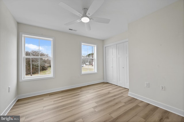 unfurnished bedroom with ceiling fan, a closet, multiple windows, and light hardwood / wood-style flooring