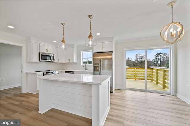 kitchen featuring white cabinetry, hanging light fixtures, and stainless steel appliances