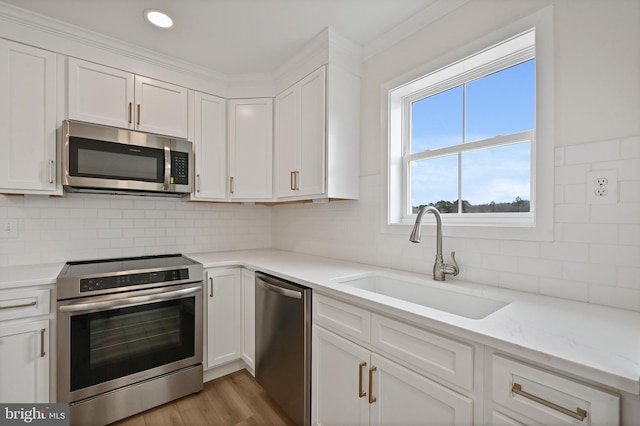 kitchen with sink, white cabinetry, light stone counters, stainless steel appliances, and decorative backsplash