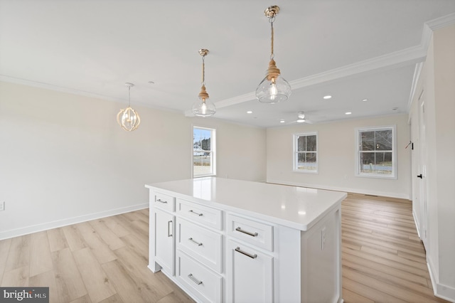 kitchen with crown molding, light hardwood / wood-style flooring, white cabinetry, a kitchen island, and decorative light fixtures