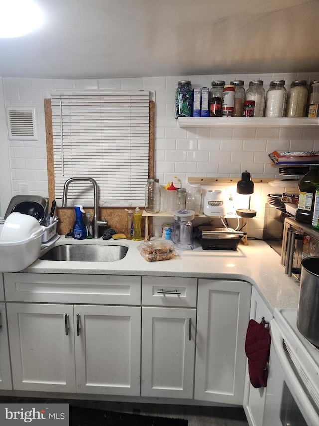 kitchen featuring white cabinets, tasteful backsplash, white range with electric cooktop, and sink