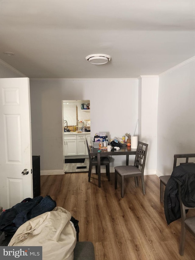 dining room with hardwood / wood-style floors, crown molding, and sink