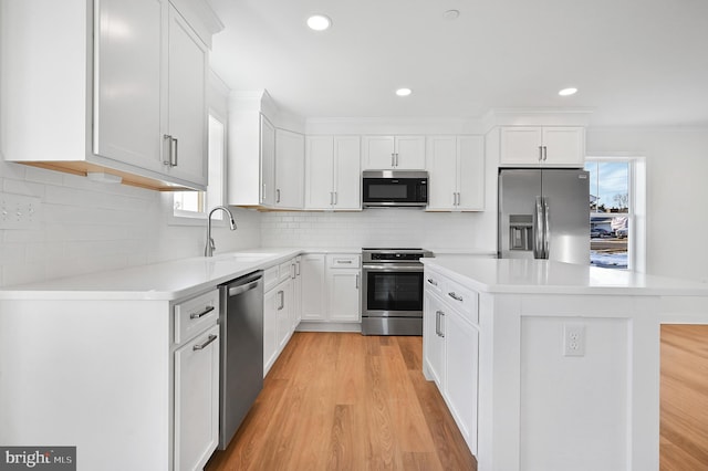 kitchen with sink, white cabinets, stainless steel appliances, and a kitchen island