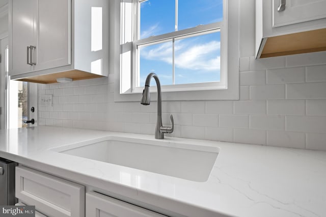 details featuring white cabinets, backsplash, and light stone counters