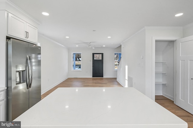 kitchen with ceiling fan, crown molding, white cabinets, and stainless steel fridge