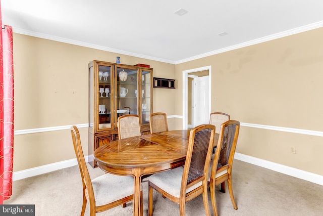 carpeted dining space with ornamental molding