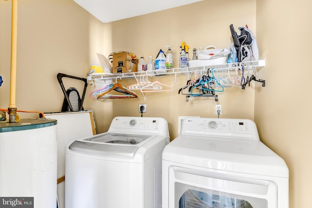 clothes washing area featuring water heater and washer and clothes dryer