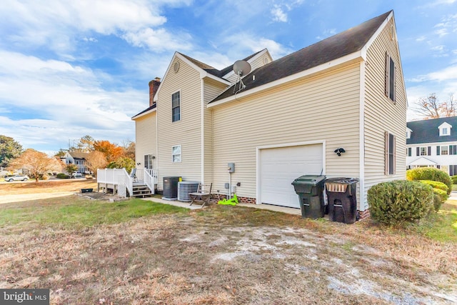 rear view of house with cooling unit, a garage, and a wooden deck