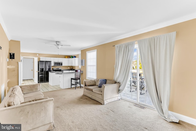 living room featuring ornamental molding, ceiling fan, and light carpet