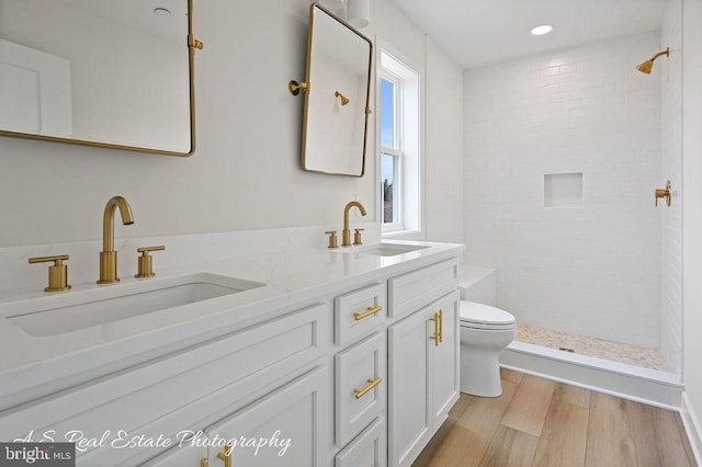 bathroom featuring vanity, hardwood / wood-style flooring, toilet, and a tile shower