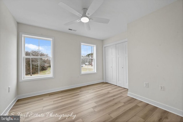 unfurnished bedroom featuring multiple windows, ceiling fan, a closet, and light hardwood / wood-style flooring